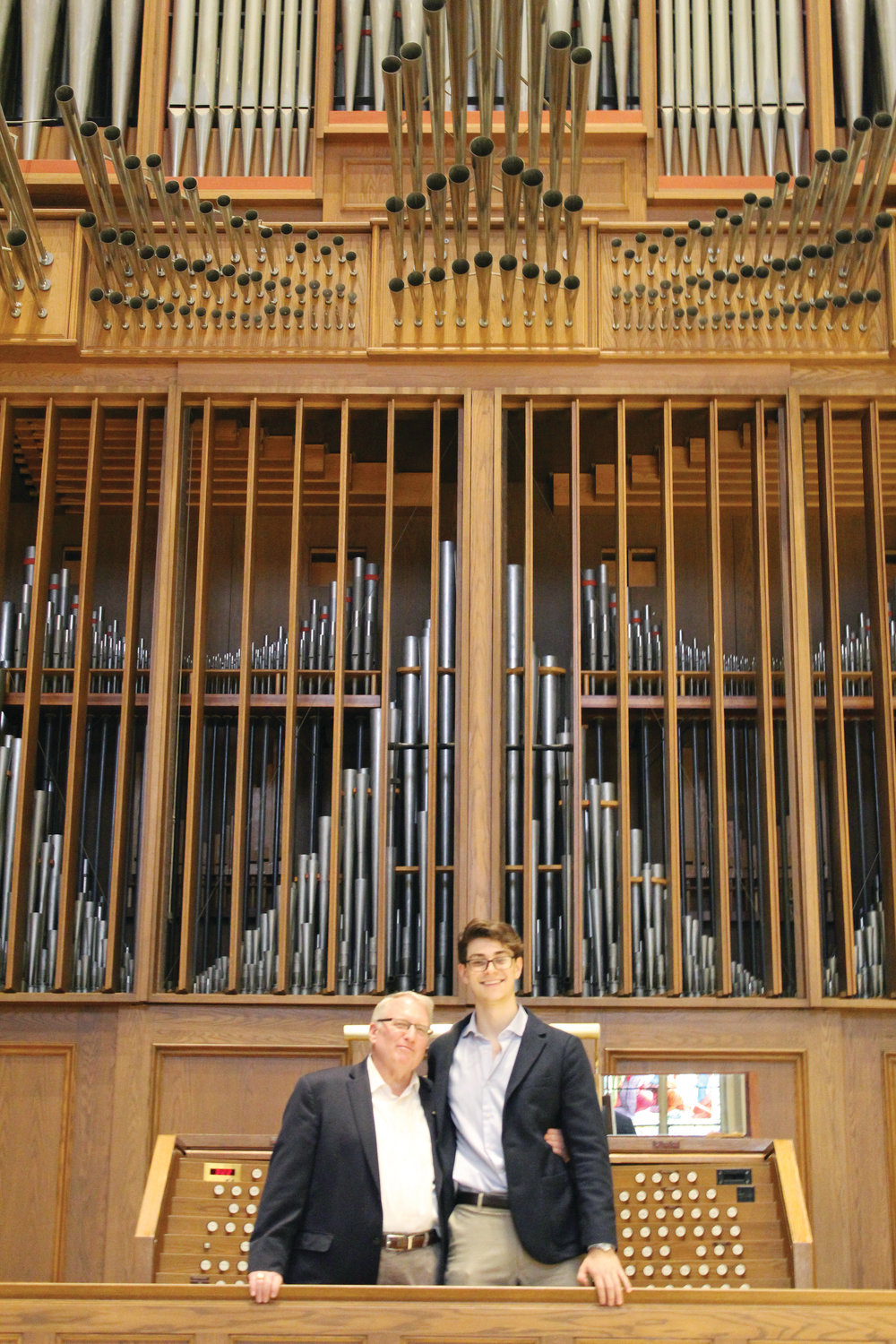 Standing in front of the historic pipe organ at the Cathedral of Saints Peter and Paul, Providence, Nathan Schneider smiles with Phillip Faraone, cathedral organist and Schneider’s music and theology teacher from The Prout School.